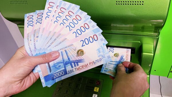 Клиент Сбербанка вносит наличные деньги в банкомат