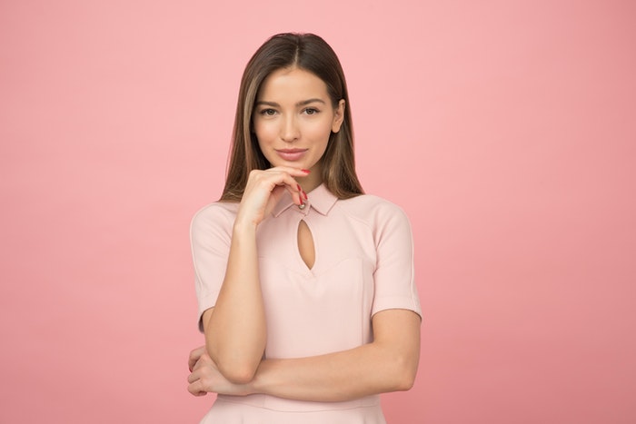 Woman posing in front of a pink background