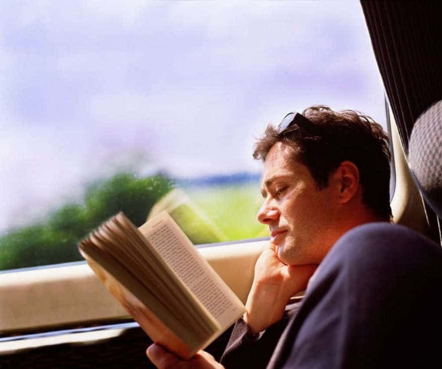Мужчина читает книгу в поезде