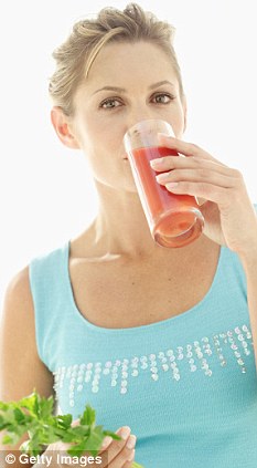 A young woman drinking tomato juice and holding a celery stick
