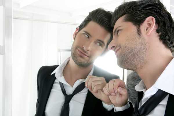 Handsome narcissistic suit proud young man looking himself in the mirror