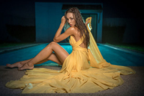 Девушка сидит на полу в вечернем платье желтого цвета