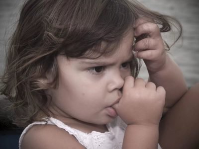 Девочка держит палец во рту