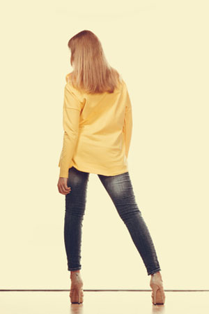 woman in long sleeve yellow shirt and faded jeans facing away