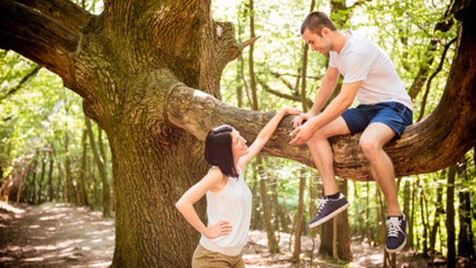 woman looking up at man siting in tree