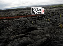 For Sale sign in town site that was destroyed by lava, with active lava flow in background