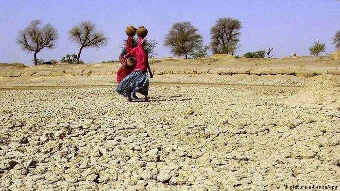 two women walk on dry soil in India