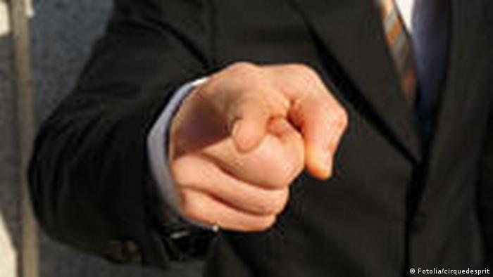 Человек в костюме показывает перед собой указательным пальцем.