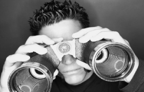 Image of man looking through binoculars depicting the need to perform a post meeting assessment.