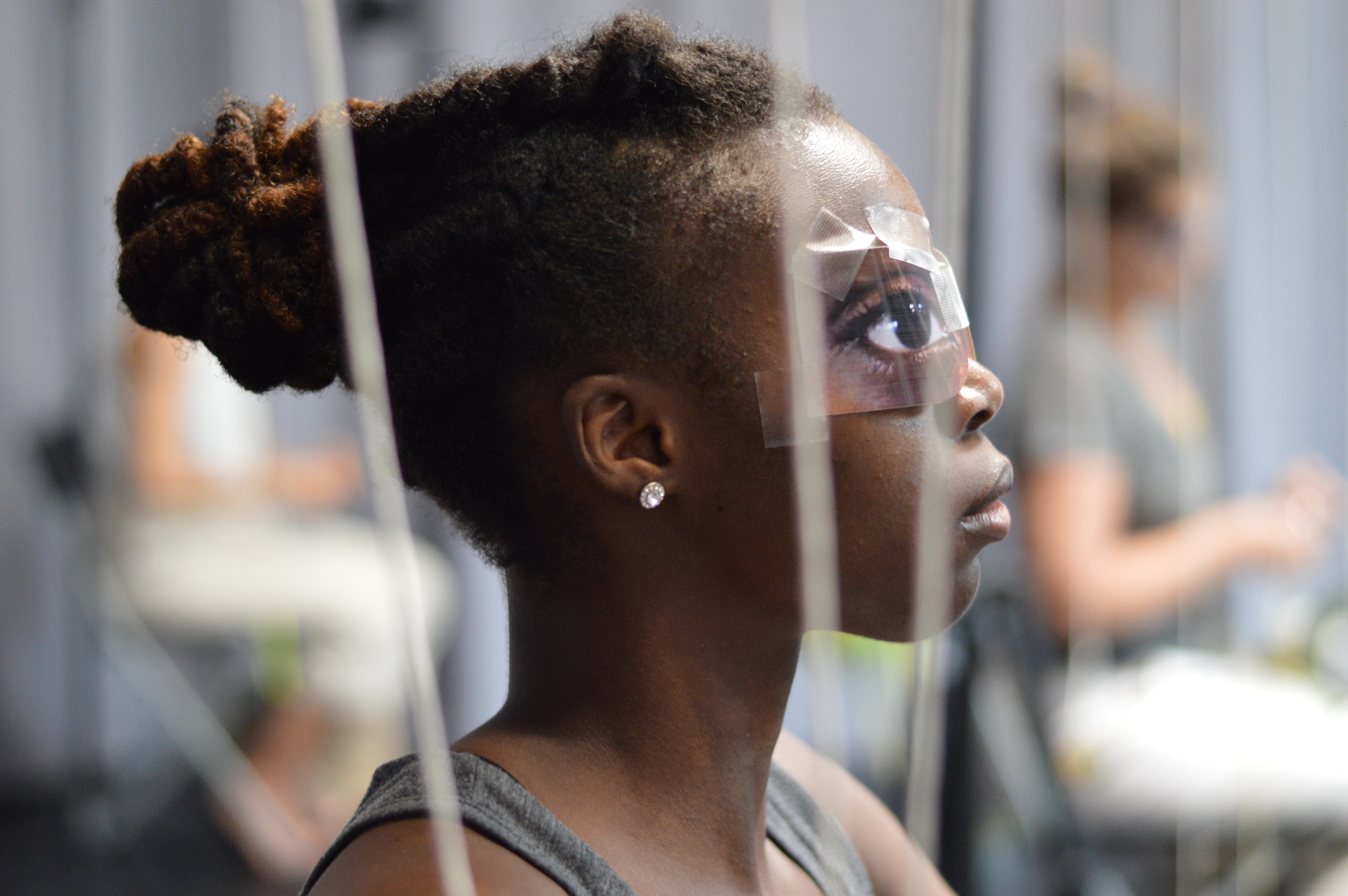 side portrait of female dancer J'nae, with painted eye mask of an eye over her face