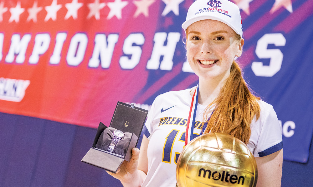 Volleyball Captain Pagie Hughes smiling and holding watch and soccer ball